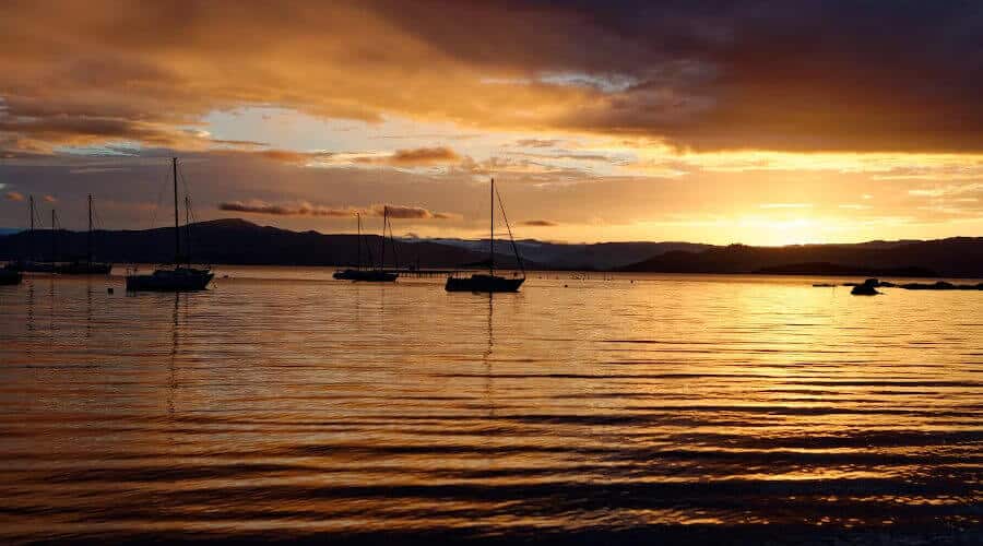 pôr do sol em tons de laranja com silhuetas de barco em santo antonio de lisboa, florianópolis, brasil